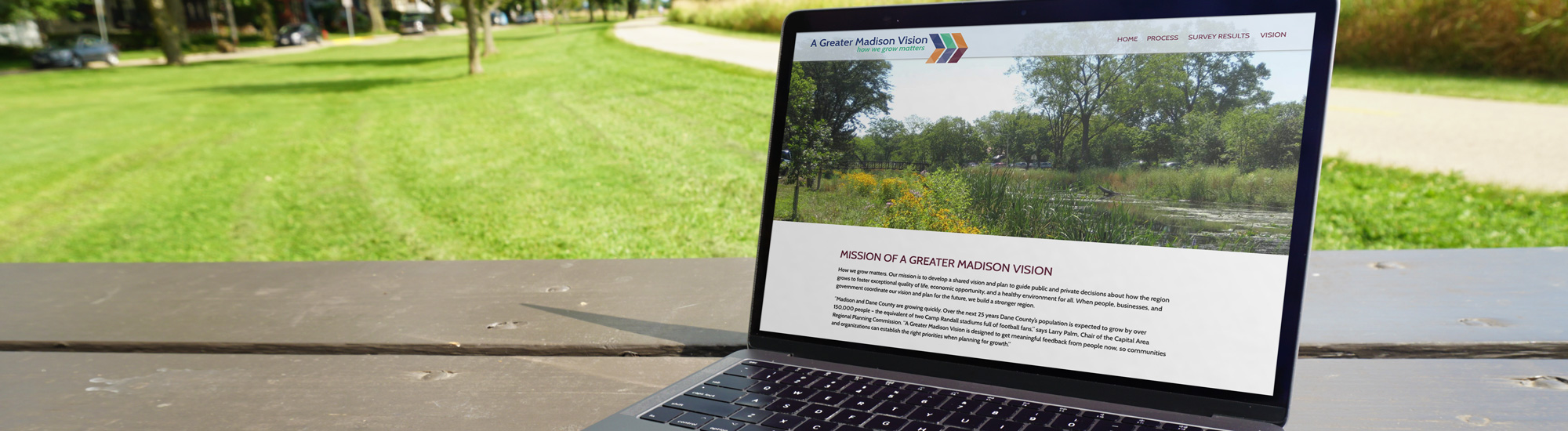 Photo of A Greater Madison Vision website on laptop on picnic table in park
