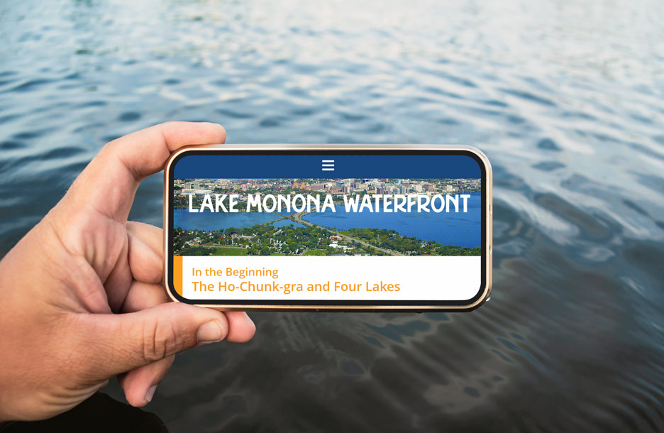 Lake Monona Waterfront website on smartphone in front of water